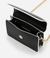 Cartera transversal pequeña de poliuretano negro con detalles en blanco y asa de cadena dorada.