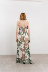 Vestido largo estampado con breteles finos, escote en V y detalle de lazo fruncido en la cintura. El estampado presenta motivos tropicales en tonos blanco, azul y marrón.