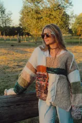 Sweater de punto grueso con diseño patchwork en tonos neutros, verde y naranja.