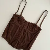 Corset marrón de encaje con breteles finos.