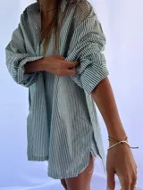 Camisa oversize a rayas verticales azules y blancas, con cuello clásico y cierre frontal con botones.