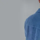 Camisa celeste de pana con corte oversize, cuello clásico, cierre frontal con botones, dos bolsillos con solapa en el pecho y mangas largas con puños abotonados.