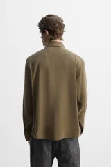Camisa negra relaxed fit confeccionada en tejido fluido con mezcla de viscosa. Tiene cuello solapa, manga larga con puño abotonado y cierre frontal con botones.