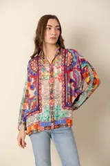 Camisa de mangas largas con cuello clásico y cierre frontal con botones. Estampado multicolor con motivos florales y geométricos.
