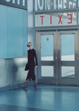 Vestido midi color marrón chocolate, de corte evasé, con cuello redondo y mangas largas. Presenta un drapeado lateral en la cintura.