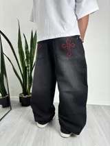 Pantalón negro de denim con corte holgado y bordados de cruces rojas en los bolsillos traseros.