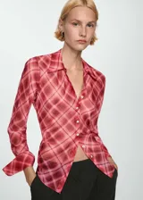 Camisa de mujer con estampado de cuadros en tonos rosa y rojo. Es de tejido fluido, con cierre de botones en la parte delantera, diseño recto, cuello camisero y manga larga abotonada.