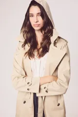 Trench color beige con doble botonadura, cinturón y cuello clásico.
