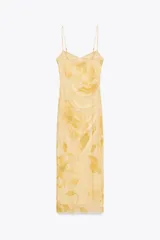 Vestido midi de tul color amarillo pálido con estampado floral, escote redondo y tirantes finos ajustables. Presenta detalle de frunces, forro interior y cierre lateral con cremallera oculta.
