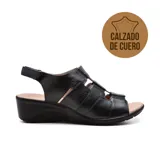 Sandalia de cuero negra con diseño de tiras entrecruzadas en el empeine, ajuste con velcro en el tobillo y plataforma baja.