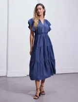 Vestido midi celeste de poliéster, con cuello a la base y escote en V. Presenta cintura con frunces y lazo de ajuste, mangas ranglan con sisa amplia y falda escalonada. Marca Emma & Michele.