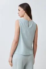 Blusa sin mangas color durazno, confeccionada en lino con efecto desflecado.