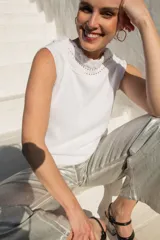 Top tejido en hilo de algodón color blanco, sin mangas, con cuello alto y detalle de trenza en el escote y espalda baja.