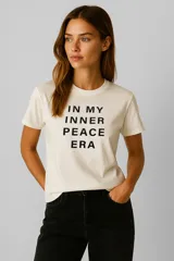 Remera color crema de algodón con cuello redondo y estampado con la frase "In my inner peace era" en letras negras.