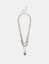 Collar corto plateado de tres capas: una de strass, otra con dijes de moños y una tercera con un dije de corazón con detalles grabados.