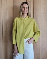 Camisa color verde oliva, de corte holgado, con cuello camisero y mangas largas con puños abotonados.