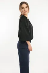 Blusa azul marino con cuello bote y mangas amplias con elástico en los puños.