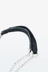 Cartera de mano o clutch color rojo oscuro (bordó) con textura de gamuza o terciopelo. Presenta tachas metálicas plateadas a lo largo del borde inferior y lateral, y un cierre perimetral plateado. Incluye una correa de hombro desmontable compuesta por una tira de material a tono y cadena metálica plateada.