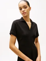 Vestido corto negro de corte evasé, con cuello tipo chomba y mangas cortas.