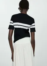 Remera de tejido de punto fino color negro con rayas horizontales blancas, cuello redondo y mangas cortas.