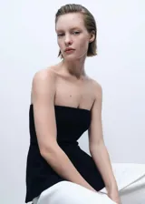 Top bandeau negro de tejido de punto fino con corte peplum. Diseño sin mangas y hombros descubiertos, ideal para eventos y fiestas.