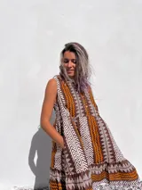 Vestido corto marrón con estampado azteca en blanco y naranja, sin mangas y con cuello redondo.