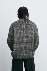 Jersey de punto negro con textura acanalada vertical, cuello redondo y manga larga.