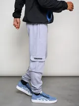Pantalón de jogging gris con bolsillos cargo laterales y logo de la marca bordado en la pierna.