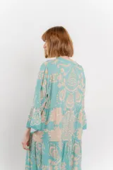 Vestido largo azul con estampado floral en tonos beige, confeccionado en viscosa. Presenta escote en V, botonadura completa en el frente y mangas largas con volados.