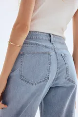 Pantalón de jean celeste de tiro alto, corte ancho y recto, con cinco bolsillos y cierre con botón.