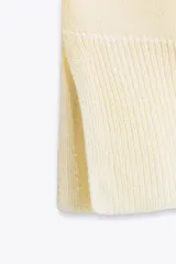 Jersey de punto color verde oliva, con cuello redondo y manga larga. Tiene bajo con aberturas laterales y acabados en rib.