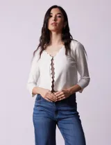 Cardigan tejido en hilado fino color blanco, marca Cable & Gauge. Abertura central con broche interno y terminación ondulada.