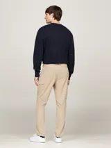 Pantalón cargo beige de corte amplio con pierna cónica, confeccionado en tejido elástico con propiedades antiarrugas y antiolores. Cuenta con cierre de cremallera y botón, dos bolsillos laterales abiertos, dos bolsillos laterales tipo cargo y dos bolsillos traseros de ojal. Logo de Tommy Hilfiger bordado en la parte trasera.