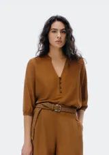 Blusa color verde claro, de mangas 3/4 con elástico en los puños, escote en V con botones y corte holgado.