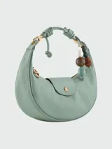 Bolso hobo de cuero color marrón, con cierre de solapa con botón a presión y correa corta para llevar al hombro. Incluye charm colgante con cuentas de madera y piedra.