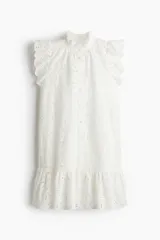 Vestido corto blanco de algodón con broderie, cuello alto con volados, mangas cortas con volados, botonadura frontal y falda con volados.