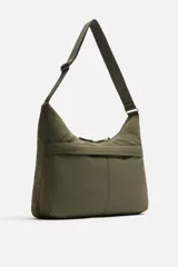Bolso de hombro color verde oliva, fabricado en tejido técnico acolchado. Tiene un compartimento principal con cierre de cremallera, un bolsillo interior con cremallera y un bolsillo frontal con cremallera. El asa de hombro es ajustable.