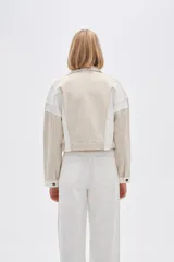 Campera corta de algodón color beige con detalles en blanco, de manga larga y cierre frontal con botones.