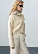 Sweater color crema de punto grueso con cuello alto.