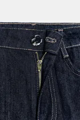 Jeans de denim oscuro, tiro alto, corte pierna ancha (wide leg) y cinco bolsillos. Presenta costuras contrastantes en color claro.