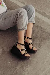Sandalias negras de plataforma con tiras de gamuza y esferas doradas decorativas.