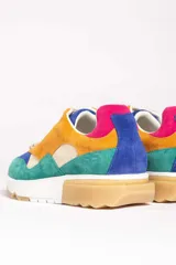 Zapatillas deportivas color mostaza con detalles en beige, verde y blanco.