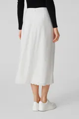 Falda midi color blanco, de lino y viscosa, con bordado en el ruedo y tajo lateral.