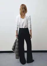 Pantalón largo de mujer, color negro, de diseño wideleg y tiro medio. Presenta detalle metálico y cierre de cremallera lateral.