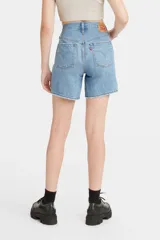 Short de jean azul claro, tiro medio, con largo hasta la mitad del muslo y corte relajado. Presenta desgaste y roturas sutiles en la zona del bolsillo delantero.