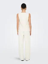 Chaleco corto color blanco hueso con cuello abierto y cierre frontal con botones. Confeccionado en tejido de punto con mezcla de poliéster y elastano. Diseño sin mangas con textura suave y calce ajustado.