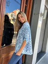 Blusa celeste con estampado floral en tonos azules, cuello mao con escote en V y cartera con botones de nácar.