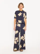 Pantalón de punto azul marino con estampado de flores blancas y marrones, cintura elastizada y corte amplio en las piernas.