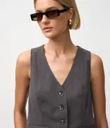 Chaleco sastre gris oscuro, ajustado al cuerpo, con escote en V, cierre frontal de cuatro botones y bolsillos embutidos.