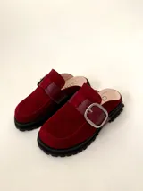 Zueco tipo mule negro, confeccionado en cuero vacuno, con puntera cuadrada y suela track gruesa. Presenta una faja ancha con hebilla metálica plateada sobre el empeine.